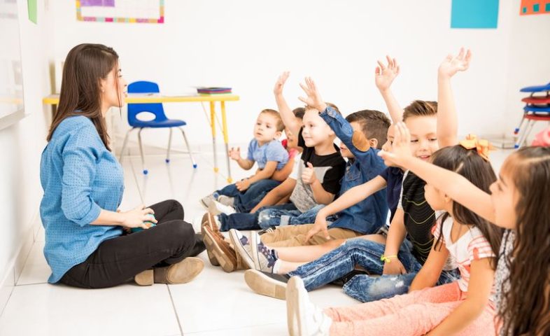Preschool students raising their hands Profile view of a group of preschool students raising their hands and trying to participate at school